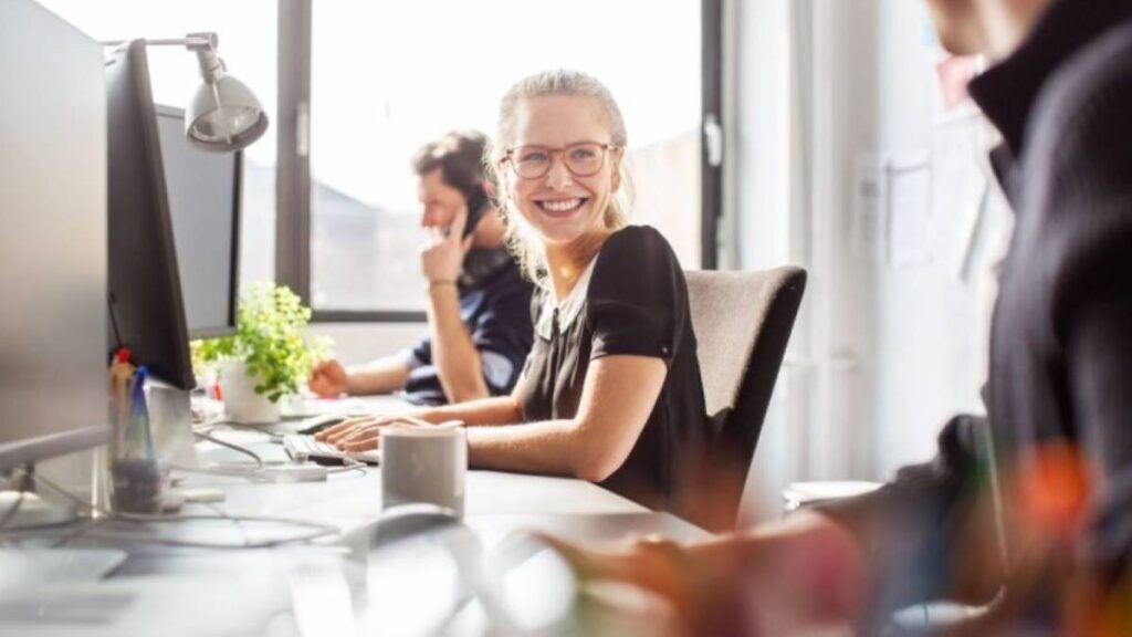 A young worker smiling at her colleague in an open office