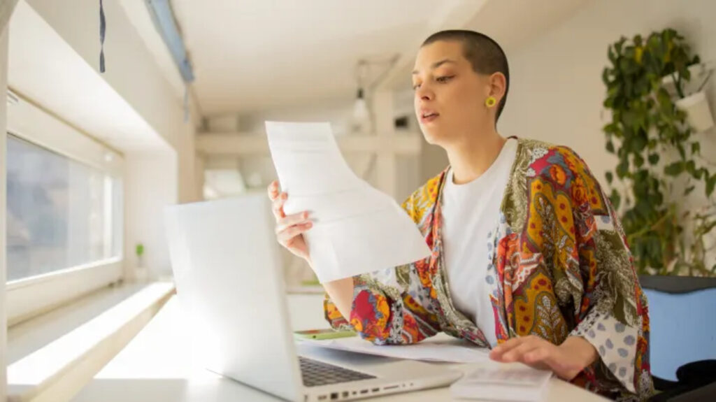 A young adult reading a paper document