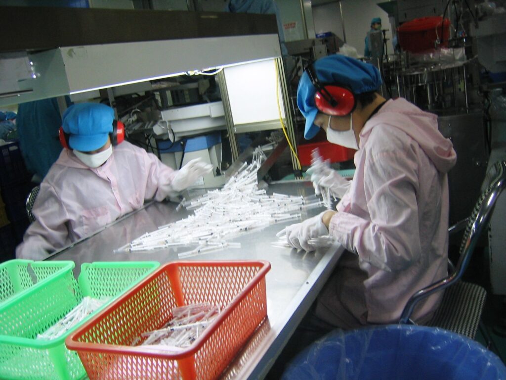 Workers running quality checks on syringes