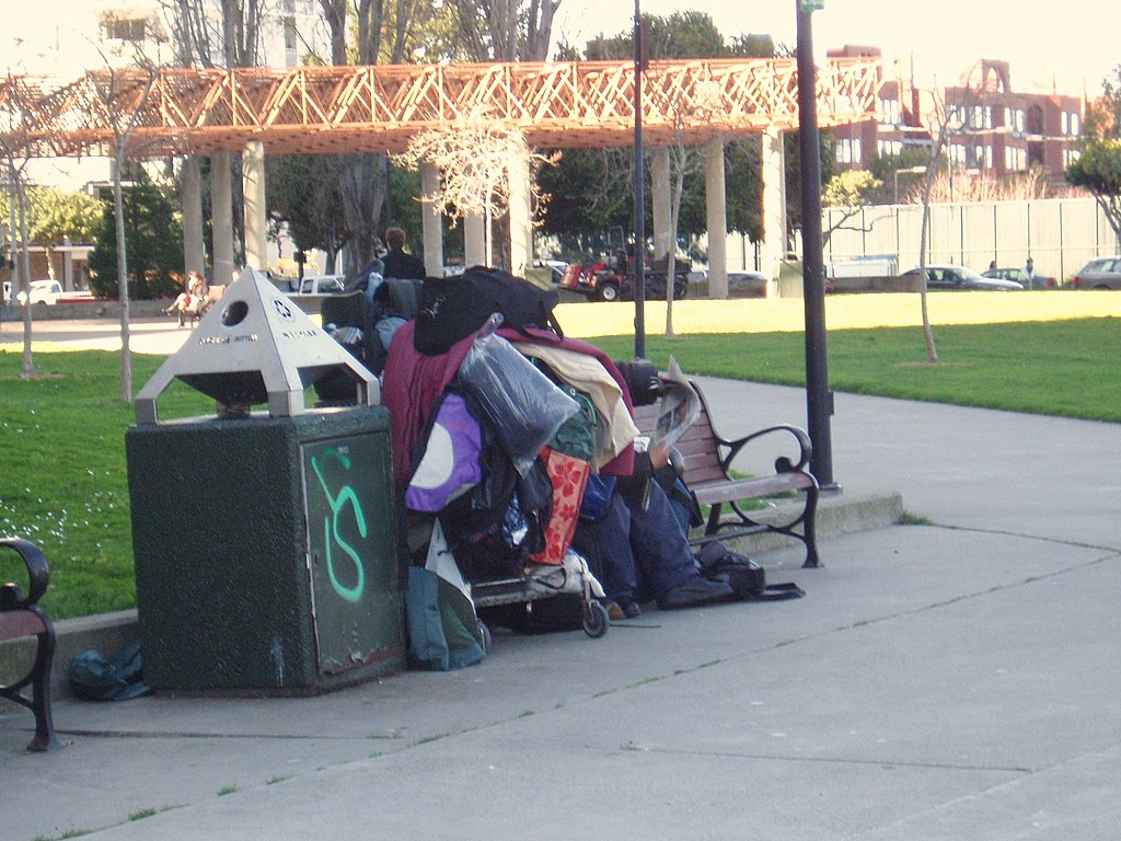 The luggage of a homeless man on a public bench