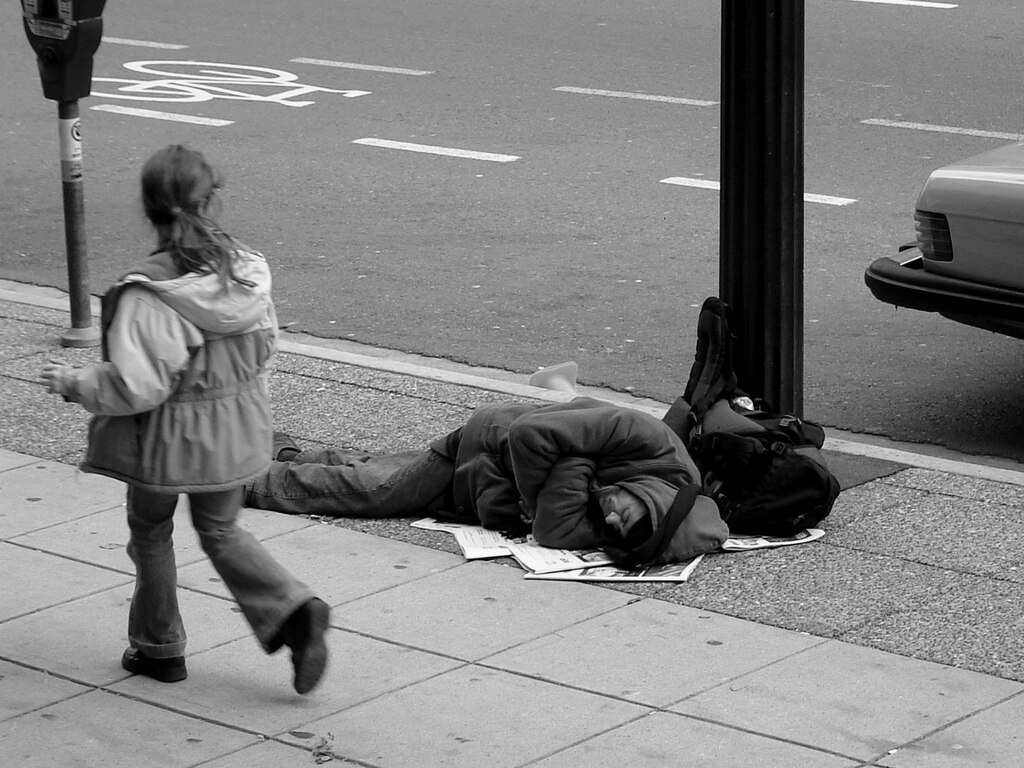 Homeless man resting on sidewalk