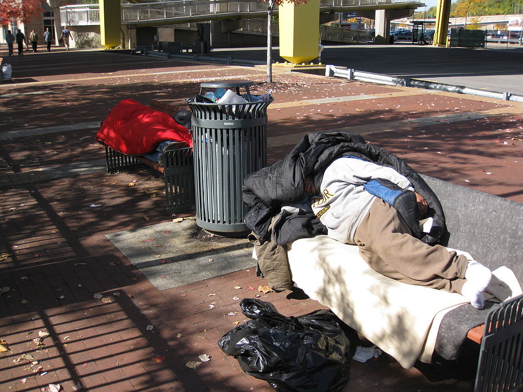 A homeless person lounging on a street bench in Pittsburgh