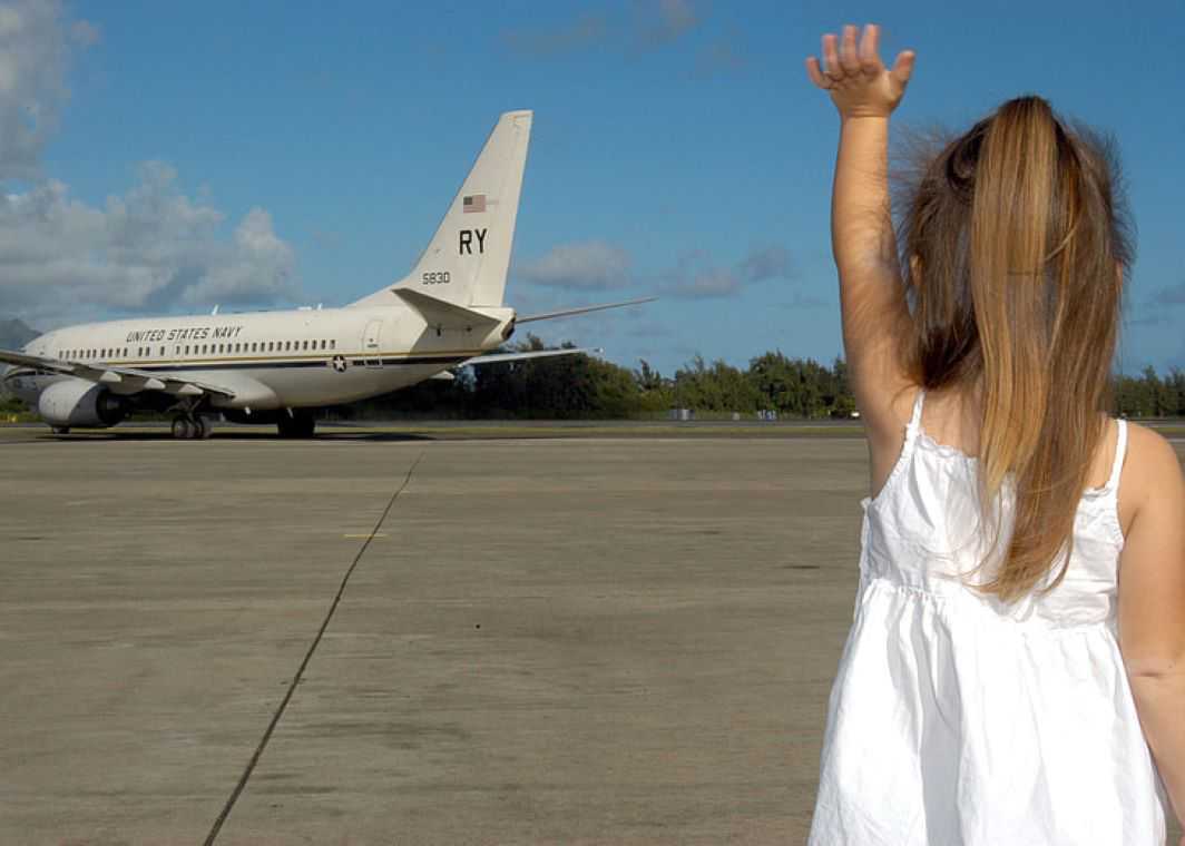 Girl in white spaghetti strap dress waving