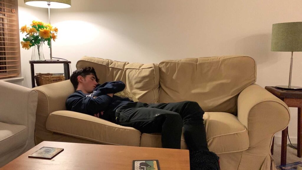 A young man sleeping on the couch 
