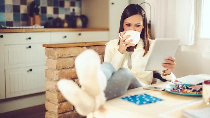 A young woman sipping beverage in a kitchen