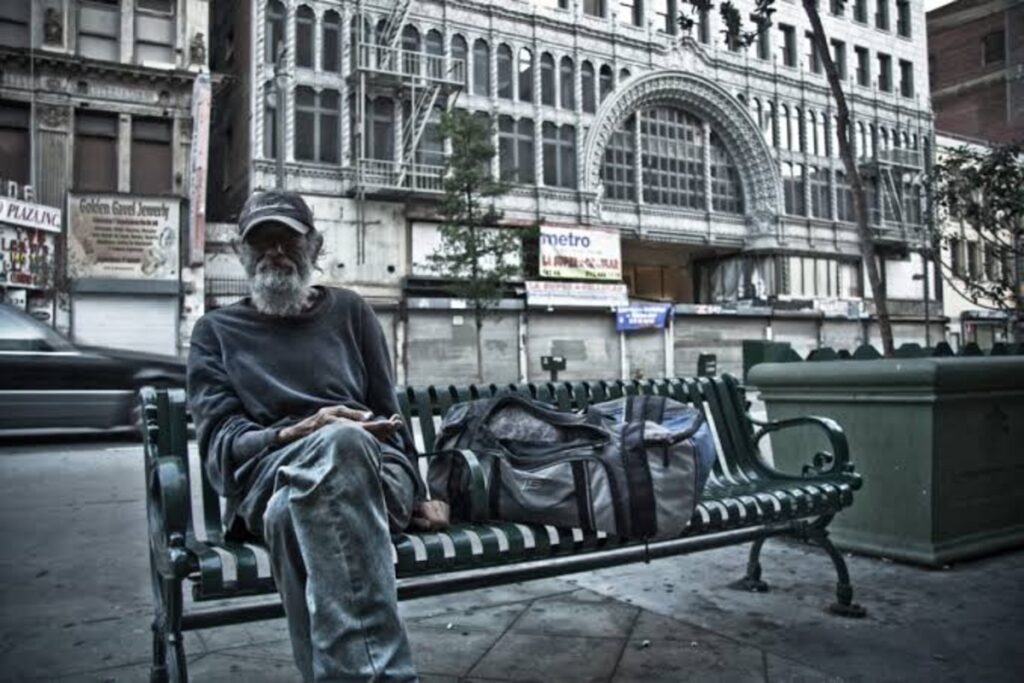 Homeless man sitting on a public bench