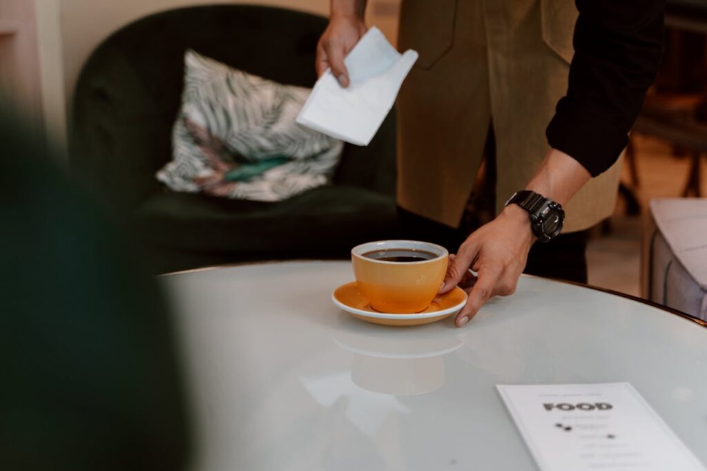 A Person Putting a Cup and Saucer on the Table