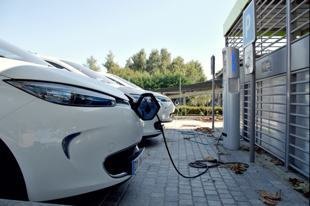 A white EV plugged in to charge