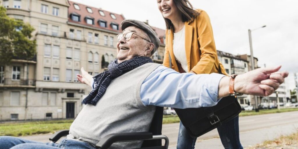 Young lady pushing a happy older man in a wheelchair