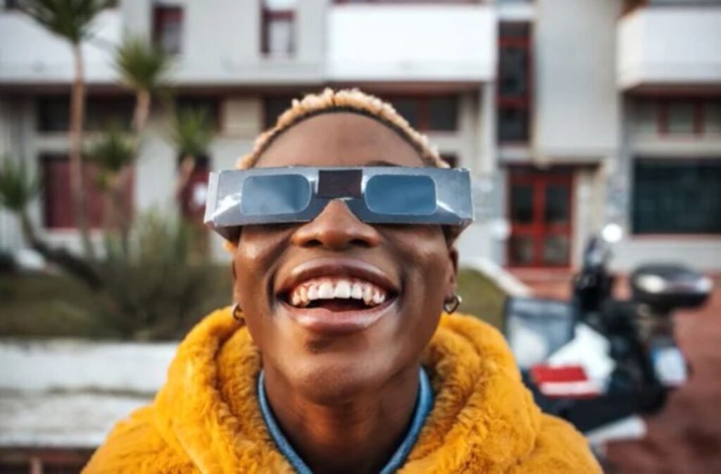 Young lady staring at the sky with solar googles