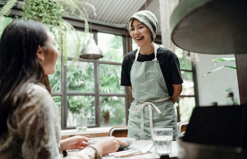 Cheerful waitress serving dish to a customer in a cafe