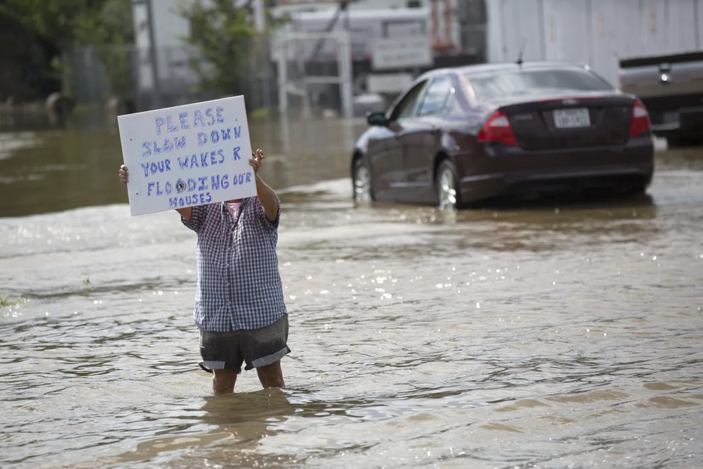 A resident holds a sign warning passersby