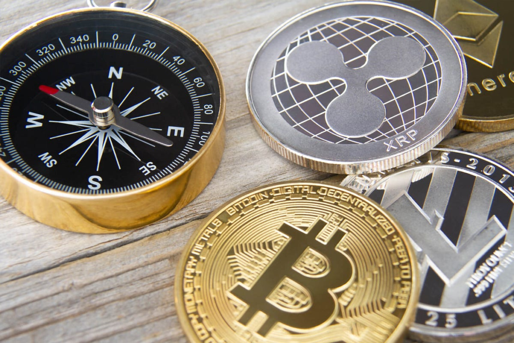 Pocket-size compass next to medallions of digital currencies