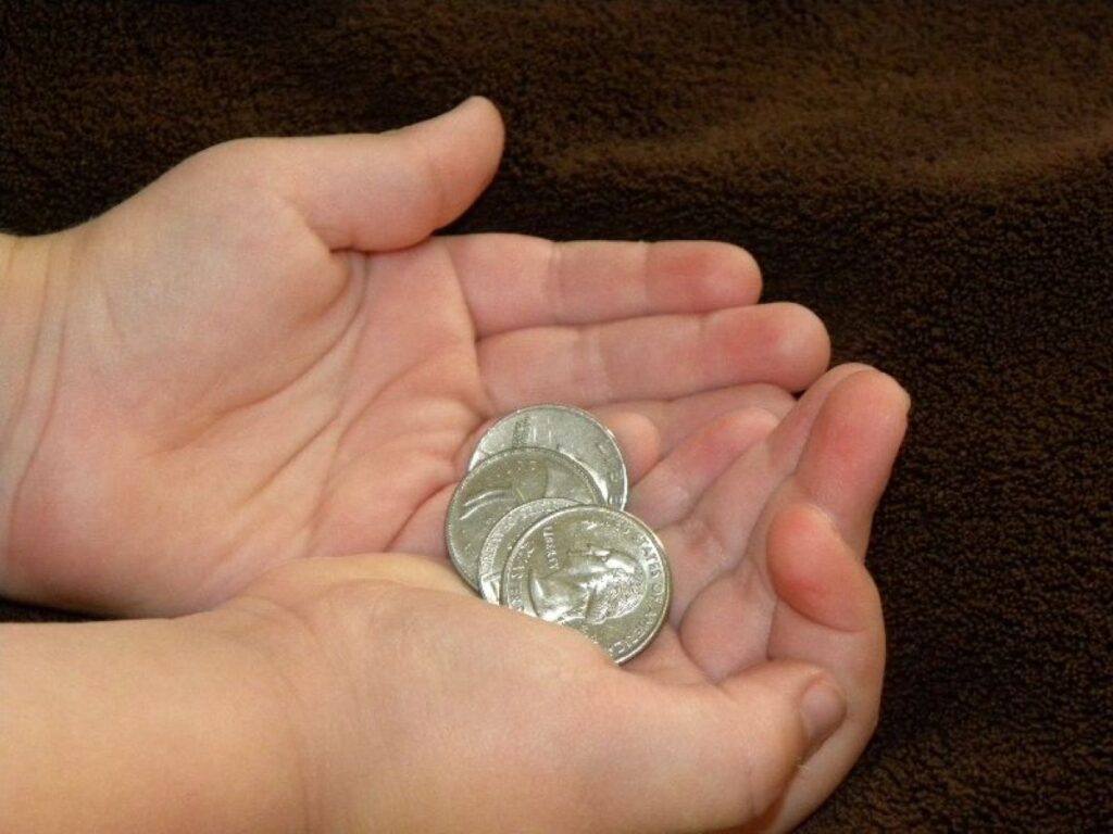 A kid holding pennies in their palm