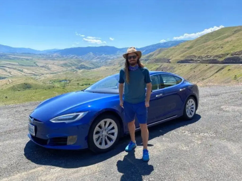 Price standing next to a sleek blue car