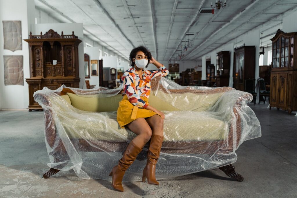 Woman Sitting On A Wooden Framed Beige Couch In A Furniture Shop