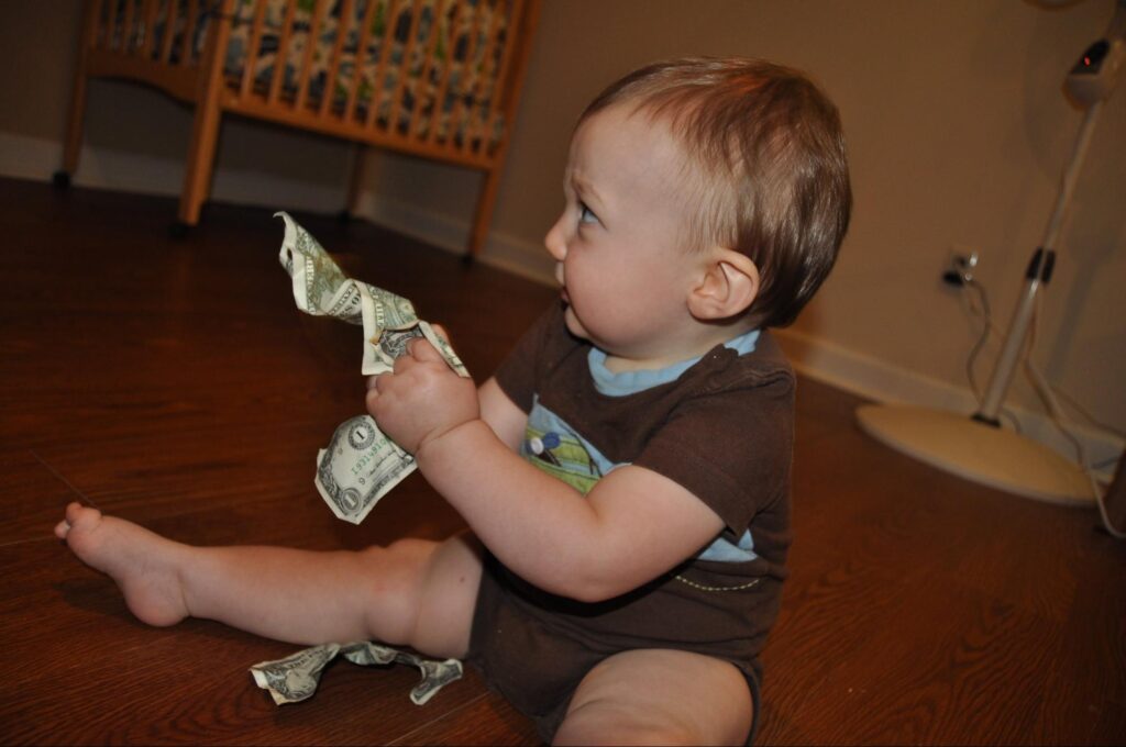 A toddler crumpling money