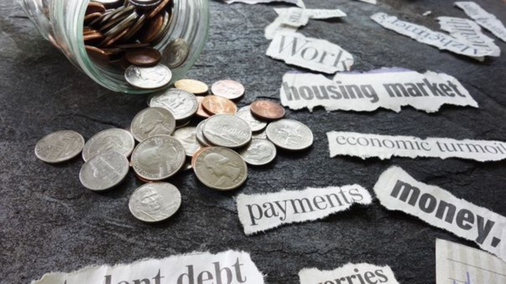 Coins pouring out of jar on a table with staples of  expenses