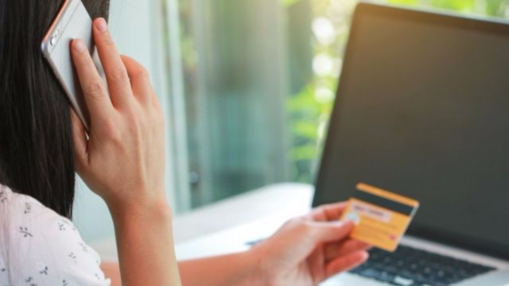 A woman on the phone and holding a credit card