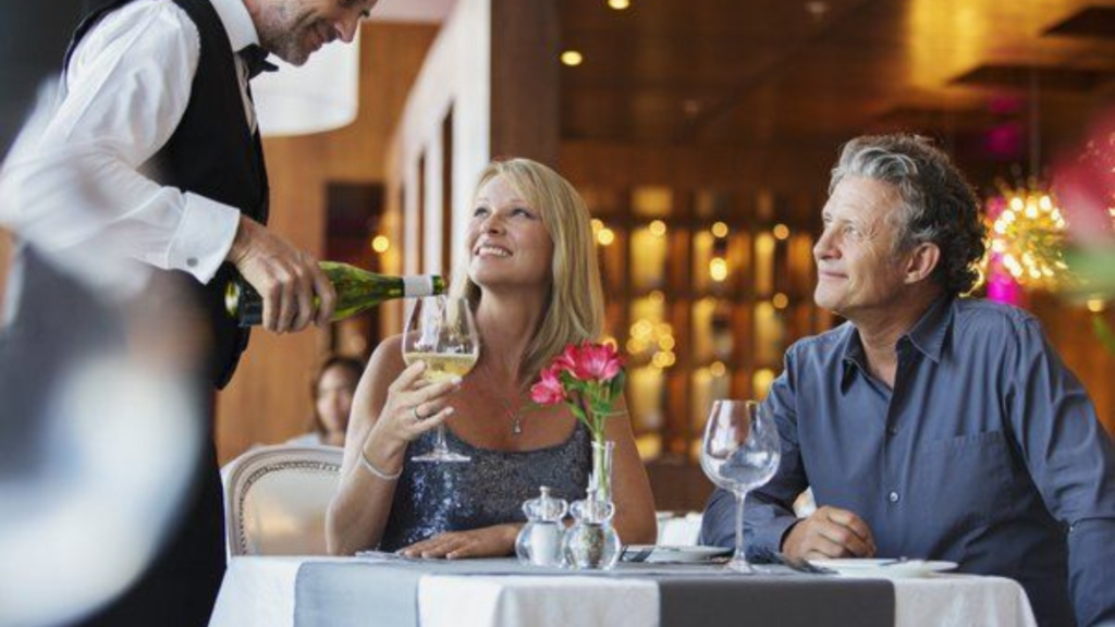 Waiter serving wine to woman with her husband at a restaurant