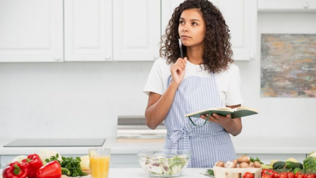 Woman holding a notepad in the kitchen and thinking