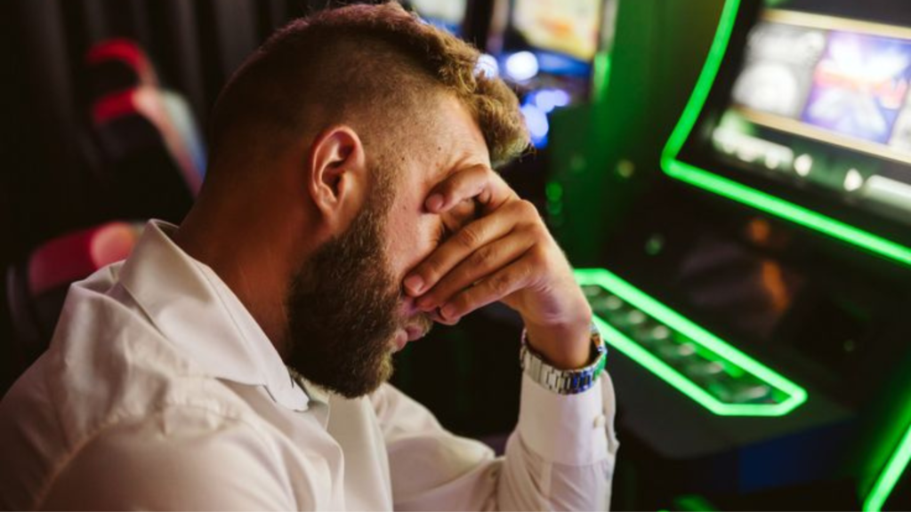 A man places his head over his hand in defeat at a casino