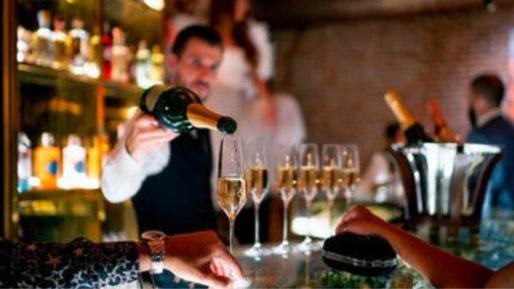 Bartender pouring out drinks in a line of wine glass cups