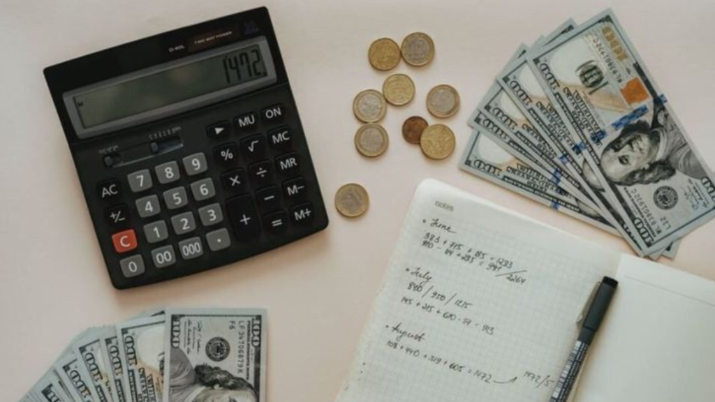 spread out cash with calculator, notepad and pen on a table