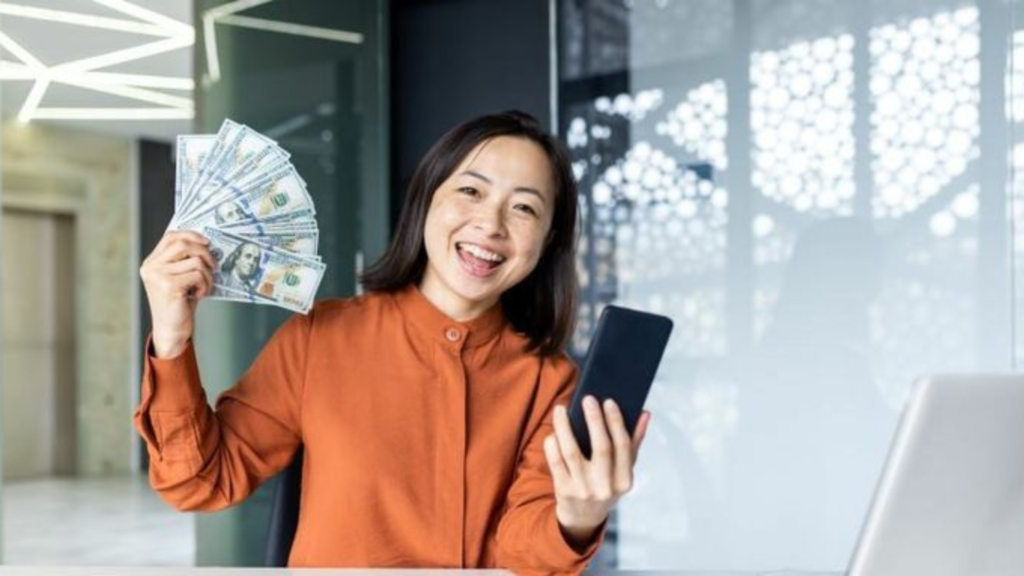 excited woman holding a phone and some cash