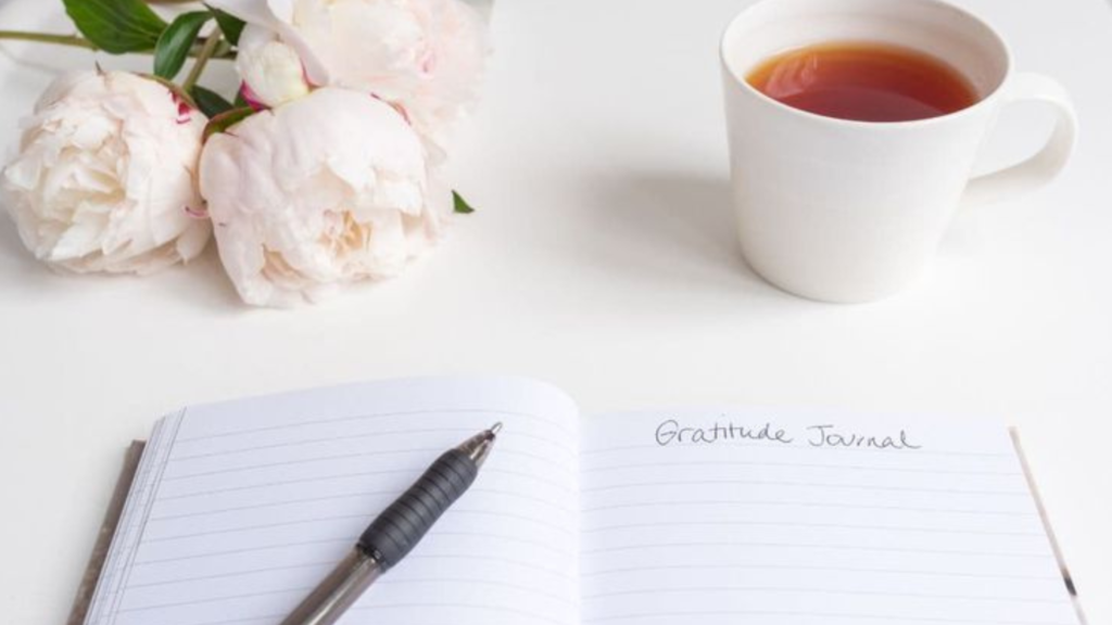 A notepad and pen on a table with a cup of coffee