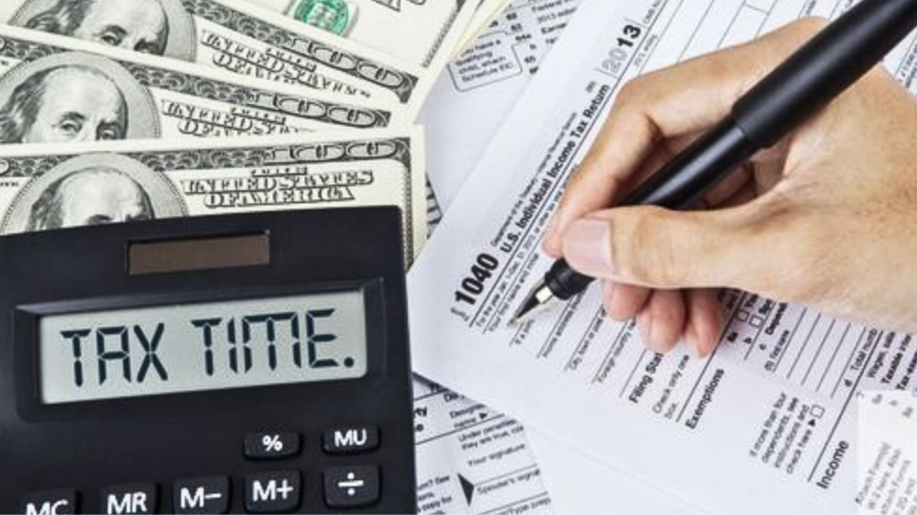 A Tax time calculator on a table with a man holding a pen over a document