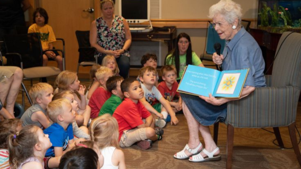 An elderly woman reading book to kids