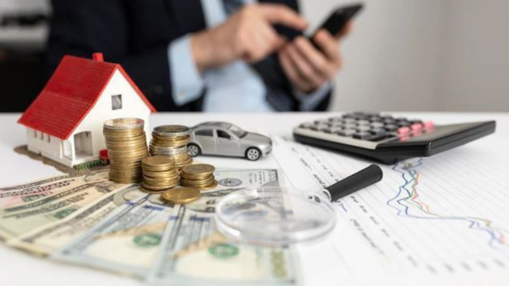 Cash, calculator with a phone and house model on the table.