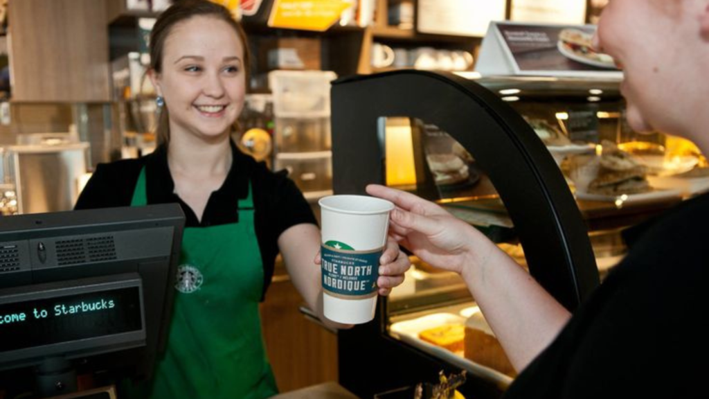 Starbucks staff handing over coffee to customer