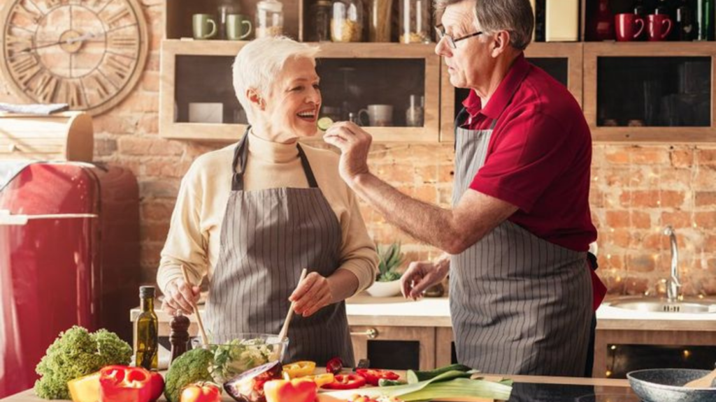 Boomer hand-feeding his wife in the kitchen while they cook