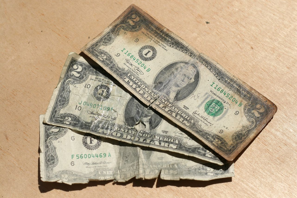 Three United States two-dollar banknotes in terrible condition