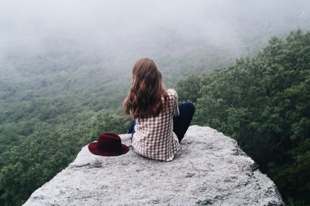 A lady sitting at the edge of a cliff