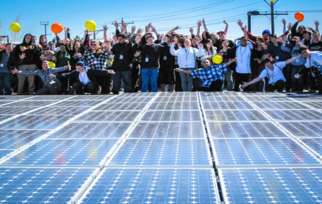 People celebrating behind an array of solar panels