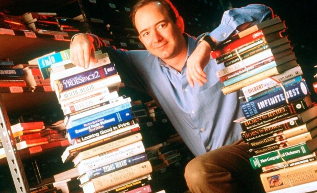 Bezos leaning on a tall pile of books