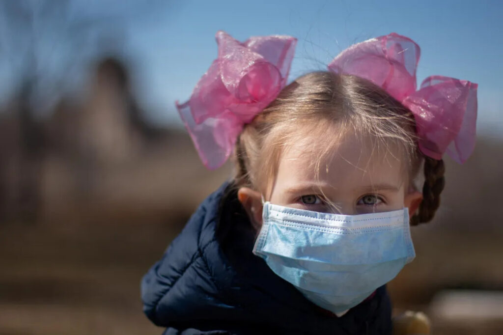 A young girl putting on a nose mask