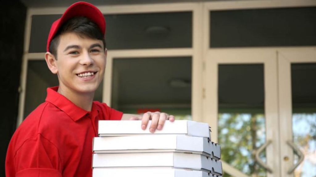 A teenage boy delivers pizza boxes