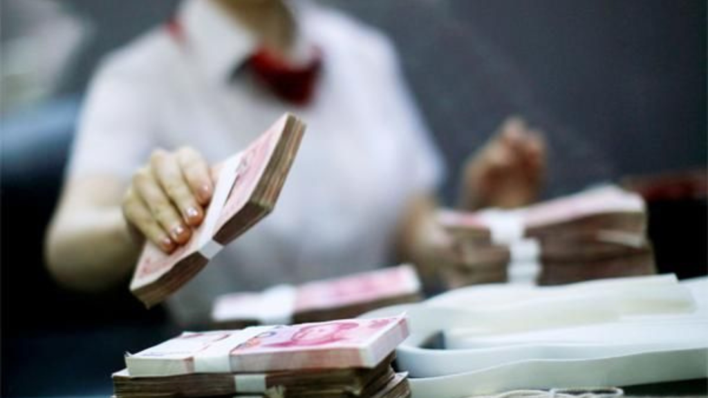 Cashier with stack of Chinese Yuan