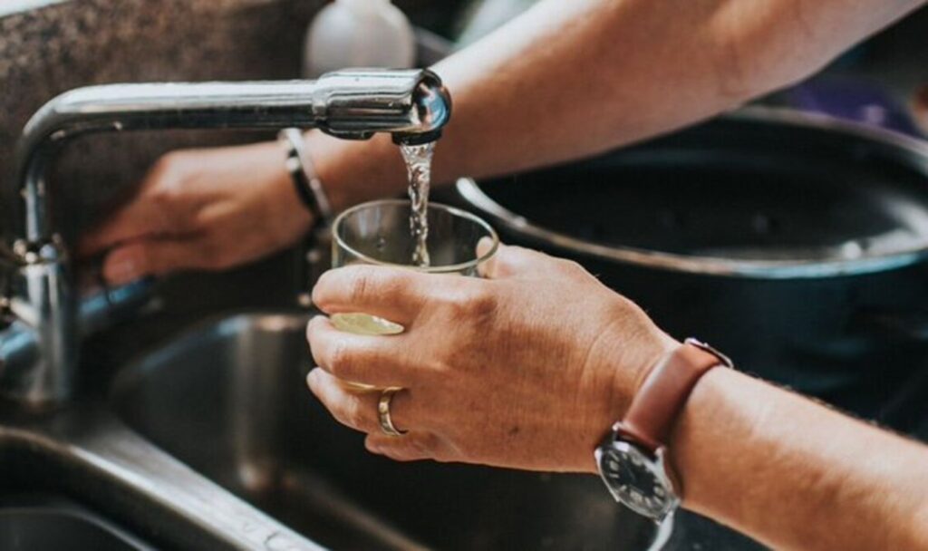 Running a faucet into a glass cup