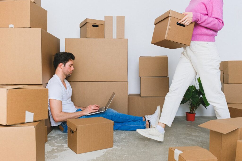 Crop woman arranging carton boxes during relocation with boyfriend