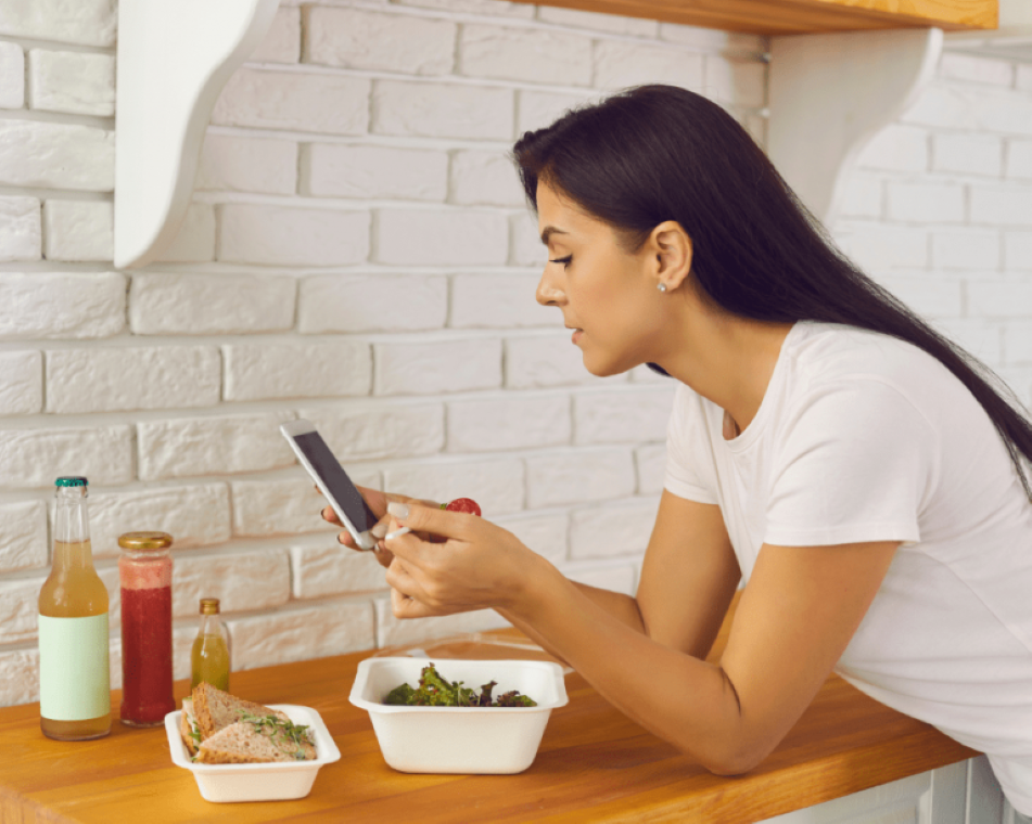 A woman fiddling with her smartphone while eating