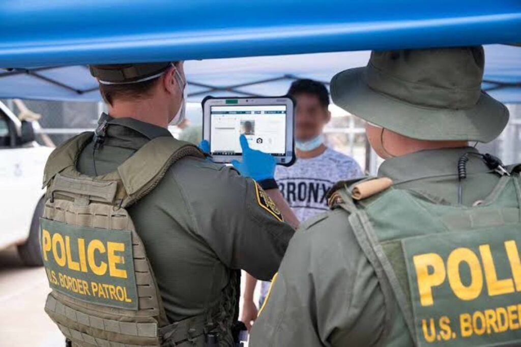 Two border patrol officers documenting a migrant