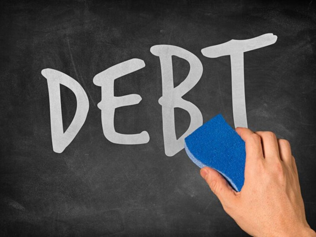 A hand trying to wipe ‘debt’ off a chalkboard