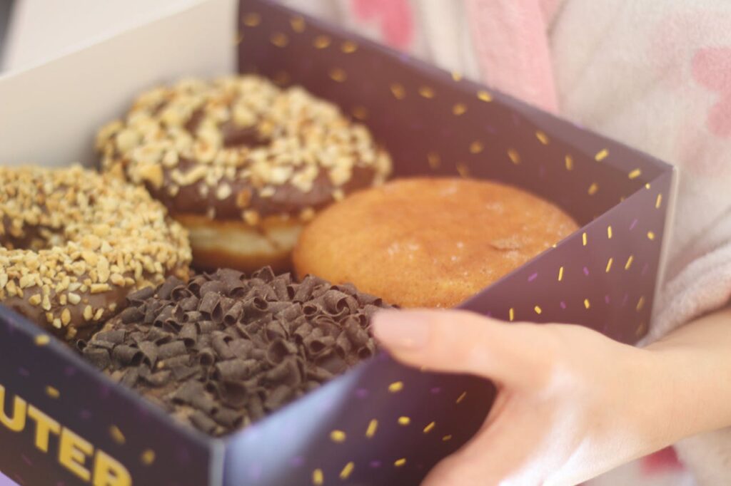 Person holding box of donuts