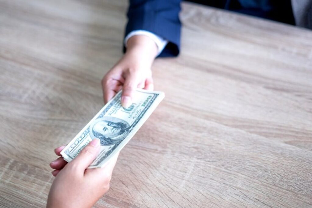 Two people exchange a wad of dollar bills