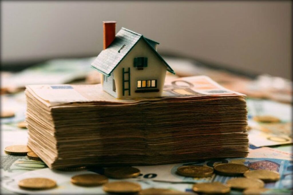 Model house sitting on top of a wad of banknotes